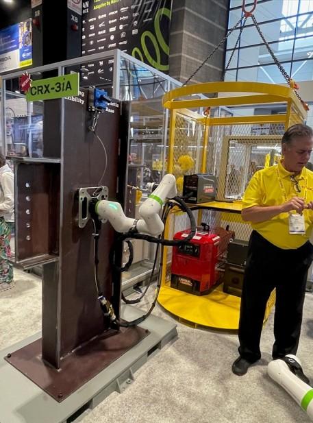 A cobot that is attached to a structural steel beam is in position to make a weld.