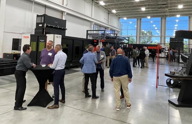 People talk with each other in the showroom at Mazak Optonics in Elgin, Ill.