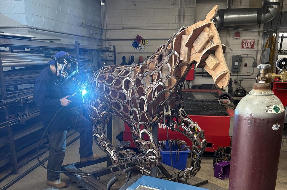 A welder works on a metal sculpture of a horse.